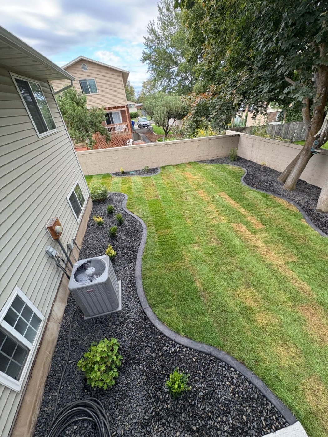 Aerial view of backyard concrete curbing bordering black rock mulch beds in Utah